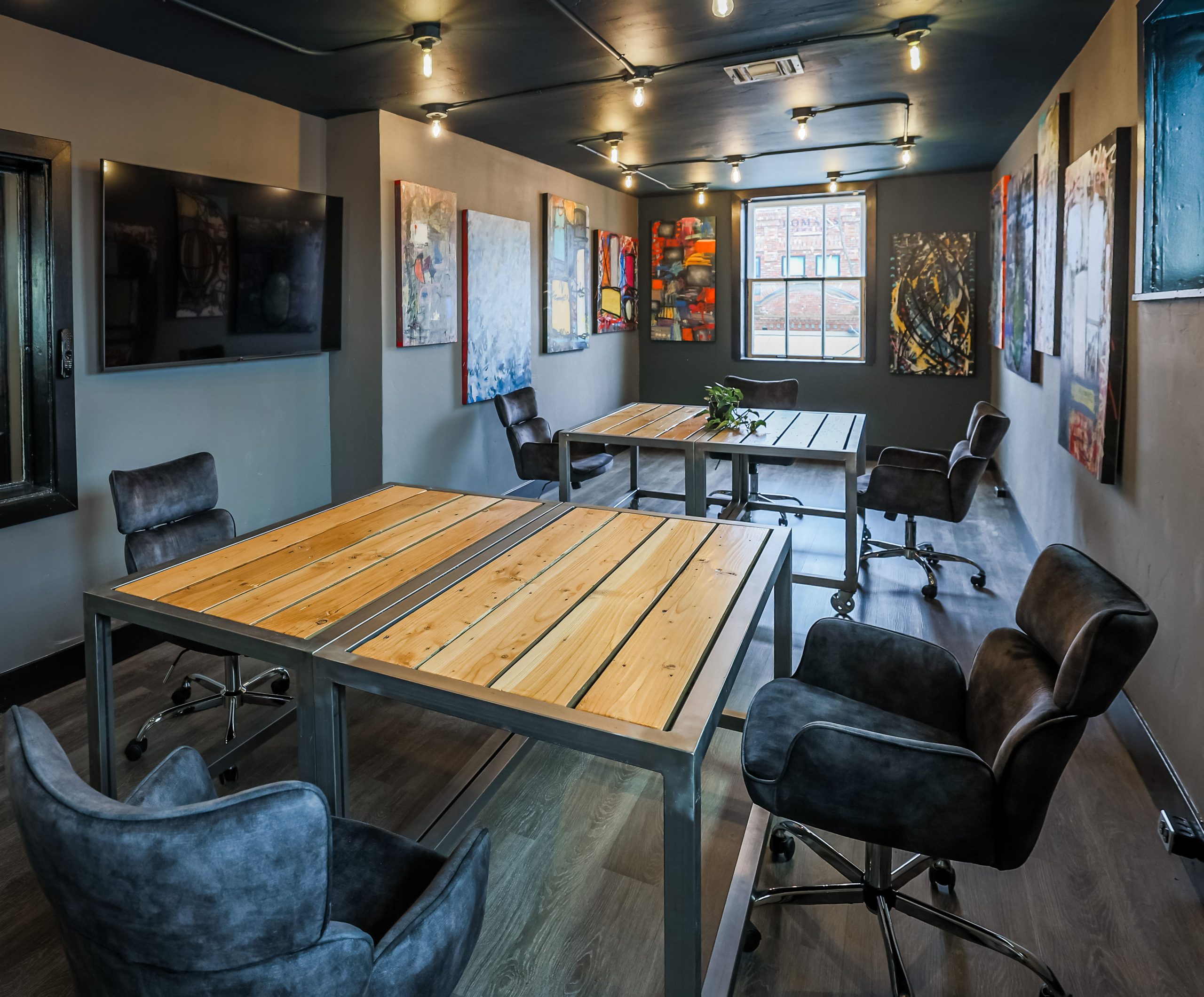 The Loft meeting room at Granite City Workspaces, equipped with ergonomic seating, industrial wood-slat tables, and presentation displays